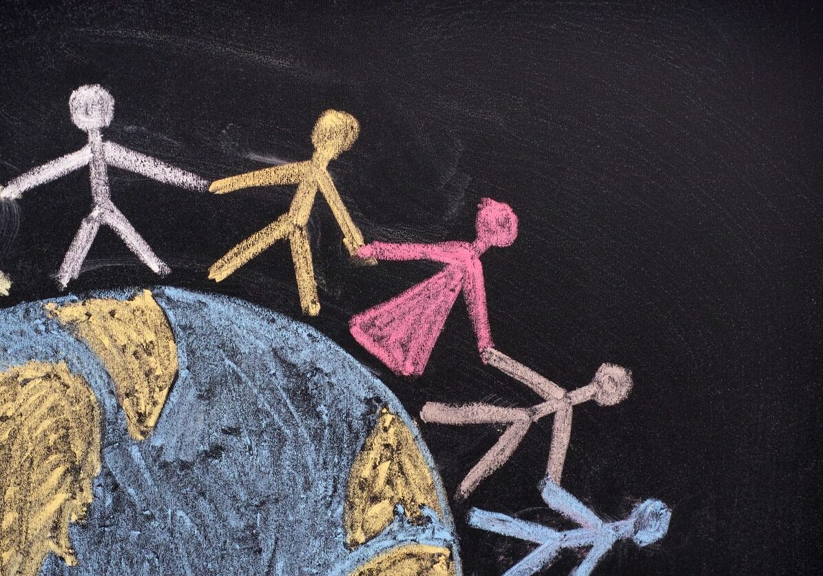 Chalk figures holding hands around a globe on a blackboard.